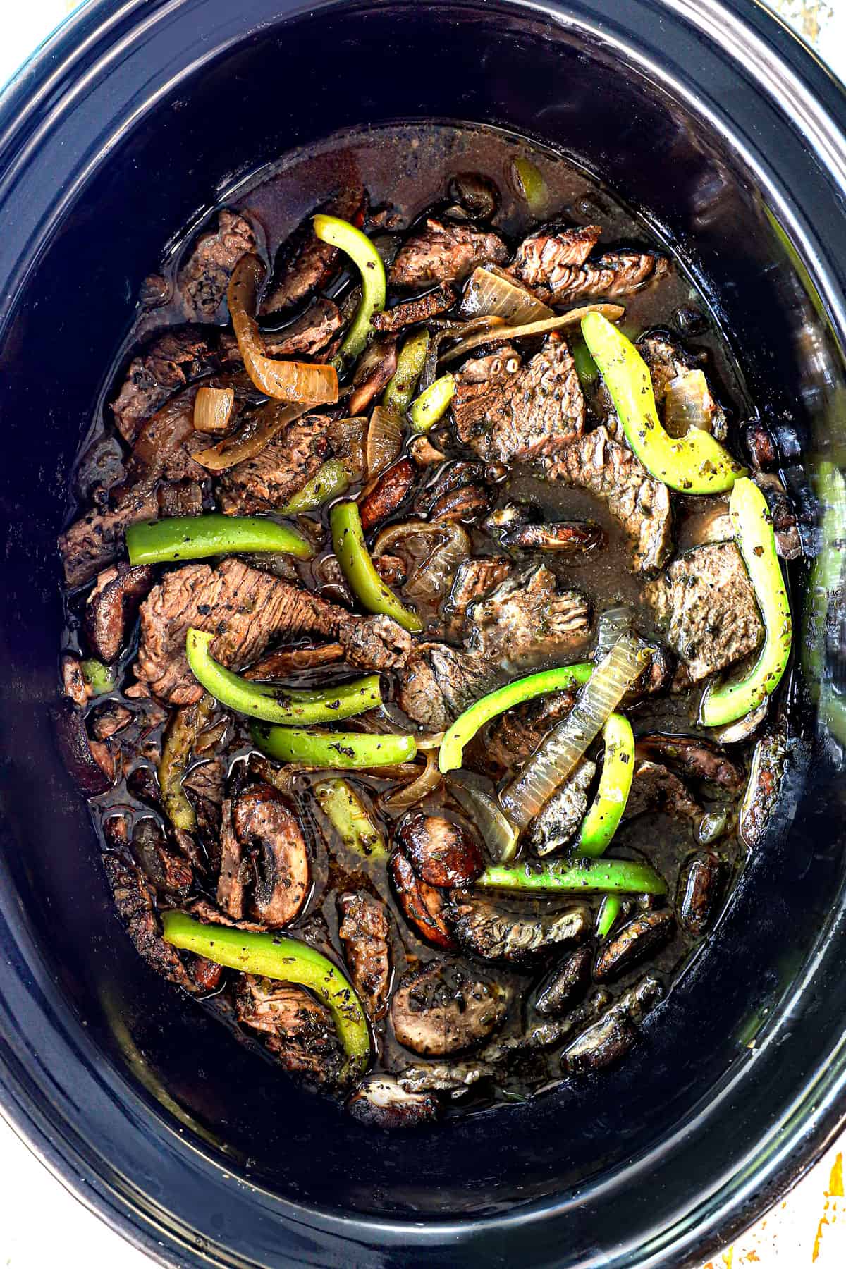 showing how to make Crockpot Philly Cheesesteak by cooking the steak, bell peppers, mushrooms and onions together