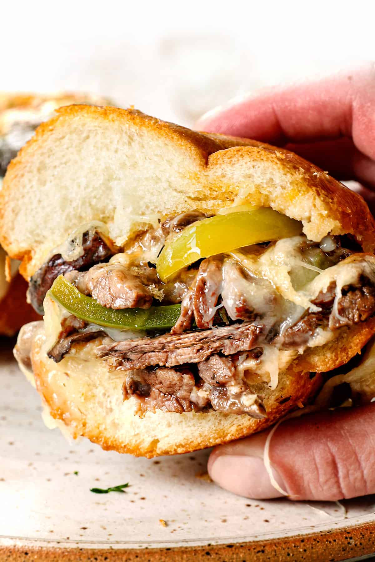 up close of a bite taken out of a Philly Cheesesteak recipe showing how tender the beef is and how cheesy it is