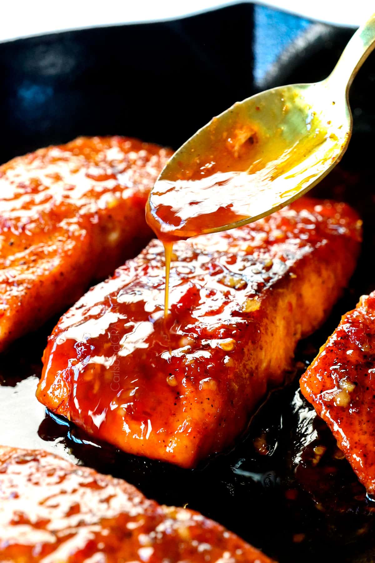 showing how to make pan seared Firecracker salmon by spooning the sauce over top the salmon