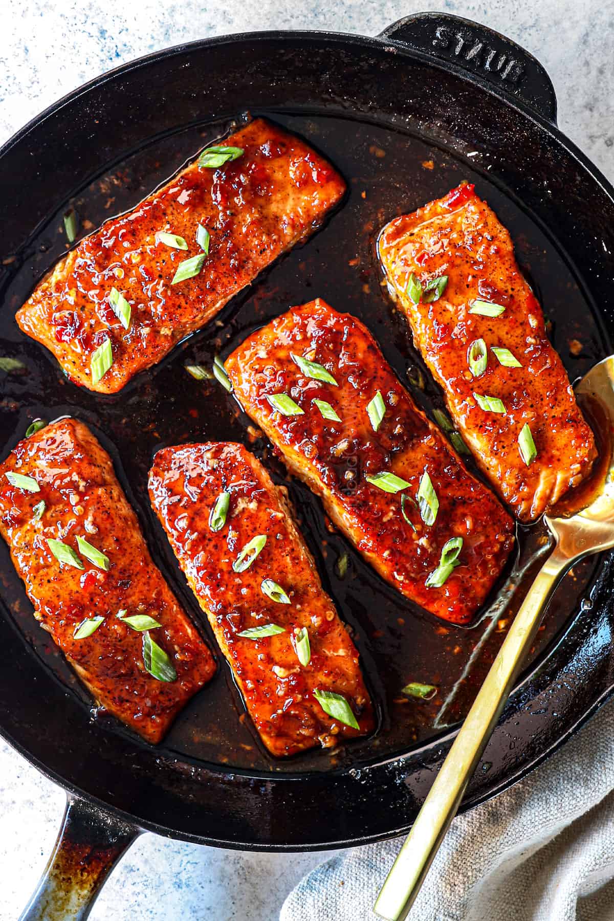 showing how to make pan seared salmon by simmering the salmon in the firecracker sauce in a skillet