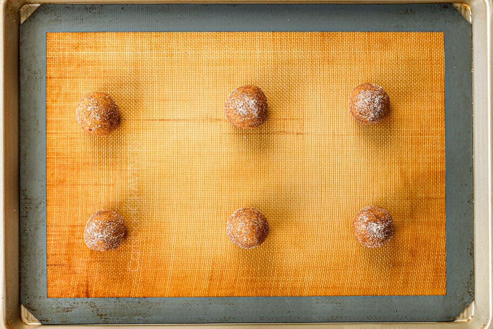 showing how to make pumpkin snickerdoodle recipe by adding dough balls to a baking sheet