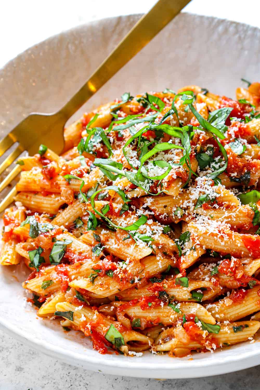 serving penne arrabbiata in a bowl with Parmesan and fresh basil