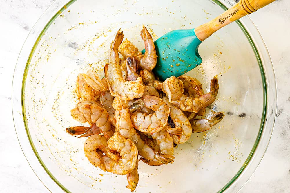 showing how to make coconut shrimp curry recipe by marinating shrimp with lime juice and curry powder