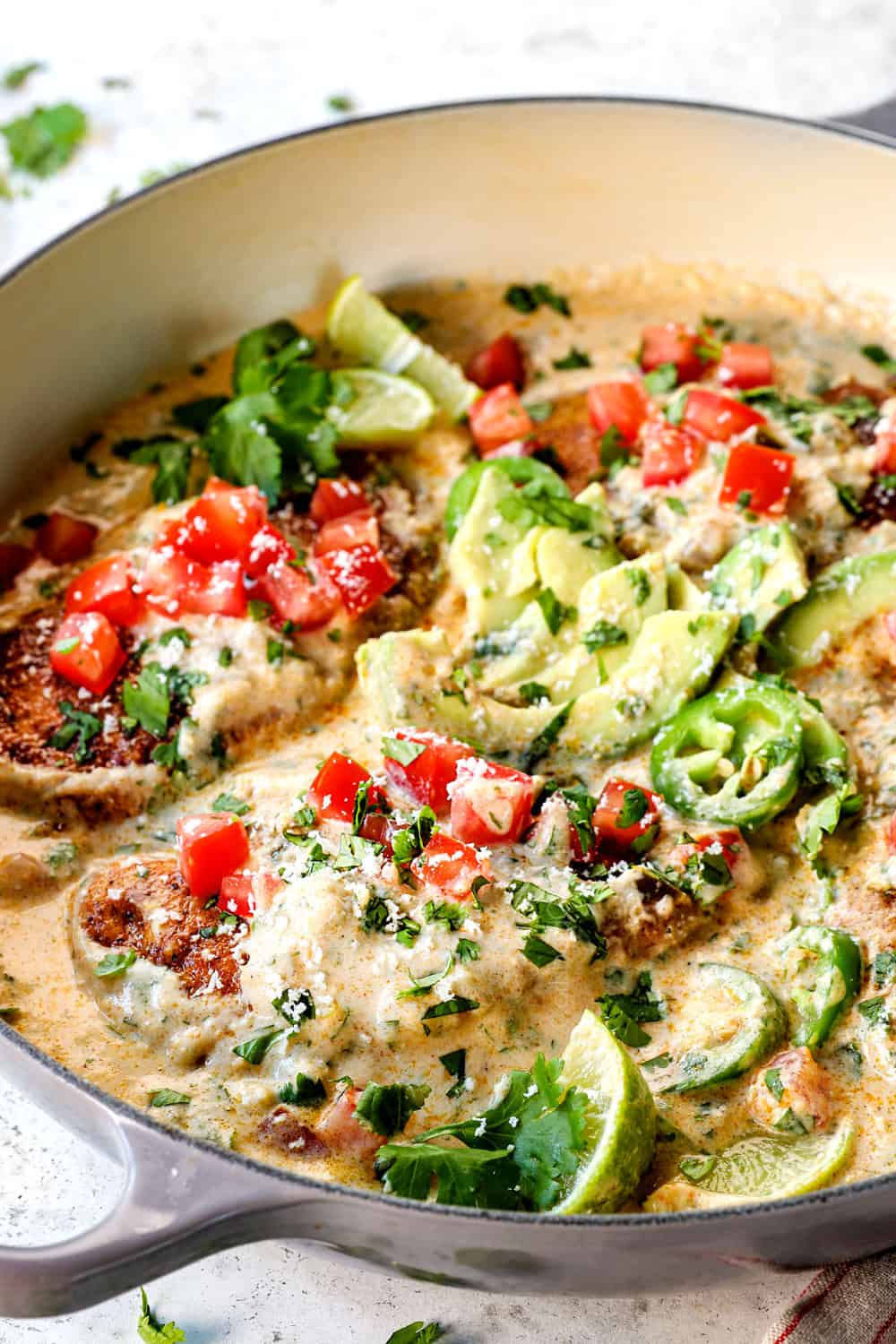 smothered chicken in creamy sauce in a skillet with juicy chicken breasts