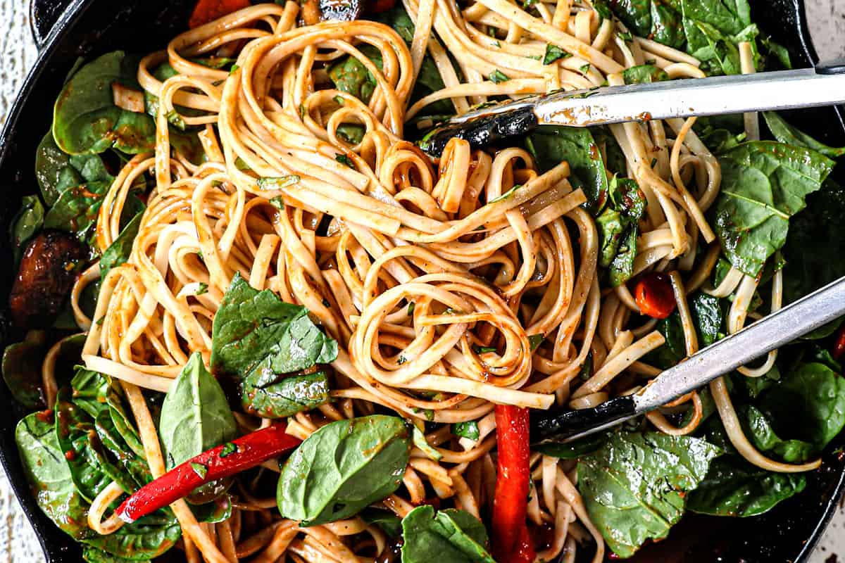 showing how to make udon noodle recipe by adding udon noodles to stir fry sauce with vegetables