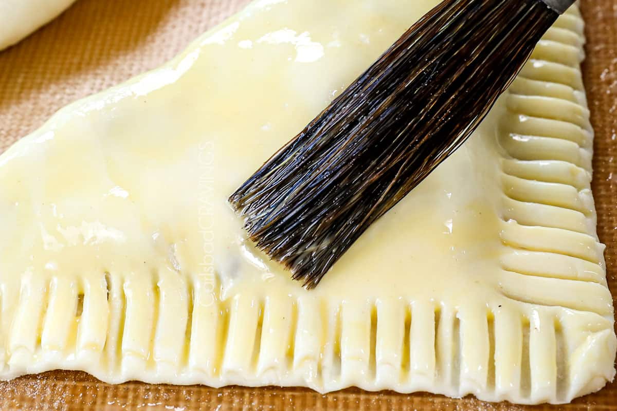 showing how to make apple turnover recipe by brushing with an egg wash