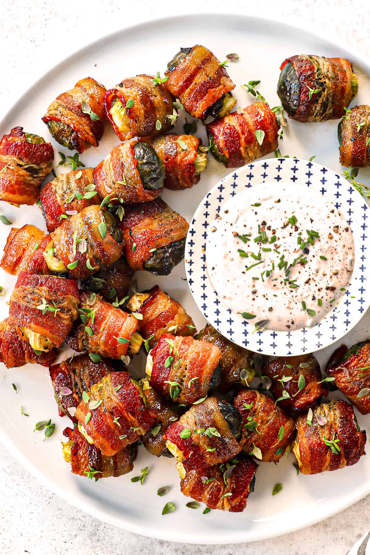 top view of serving Bacon Wrapped Brussels Sprouts on a serving platter with dip