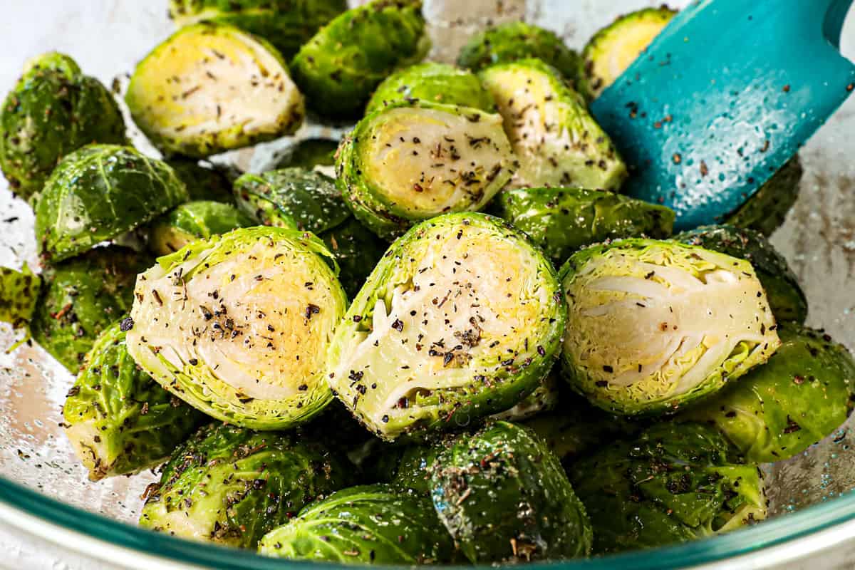 showing how to make Bacon Wrapped Brussels Sprouts by tossing with olive oil and seasonings