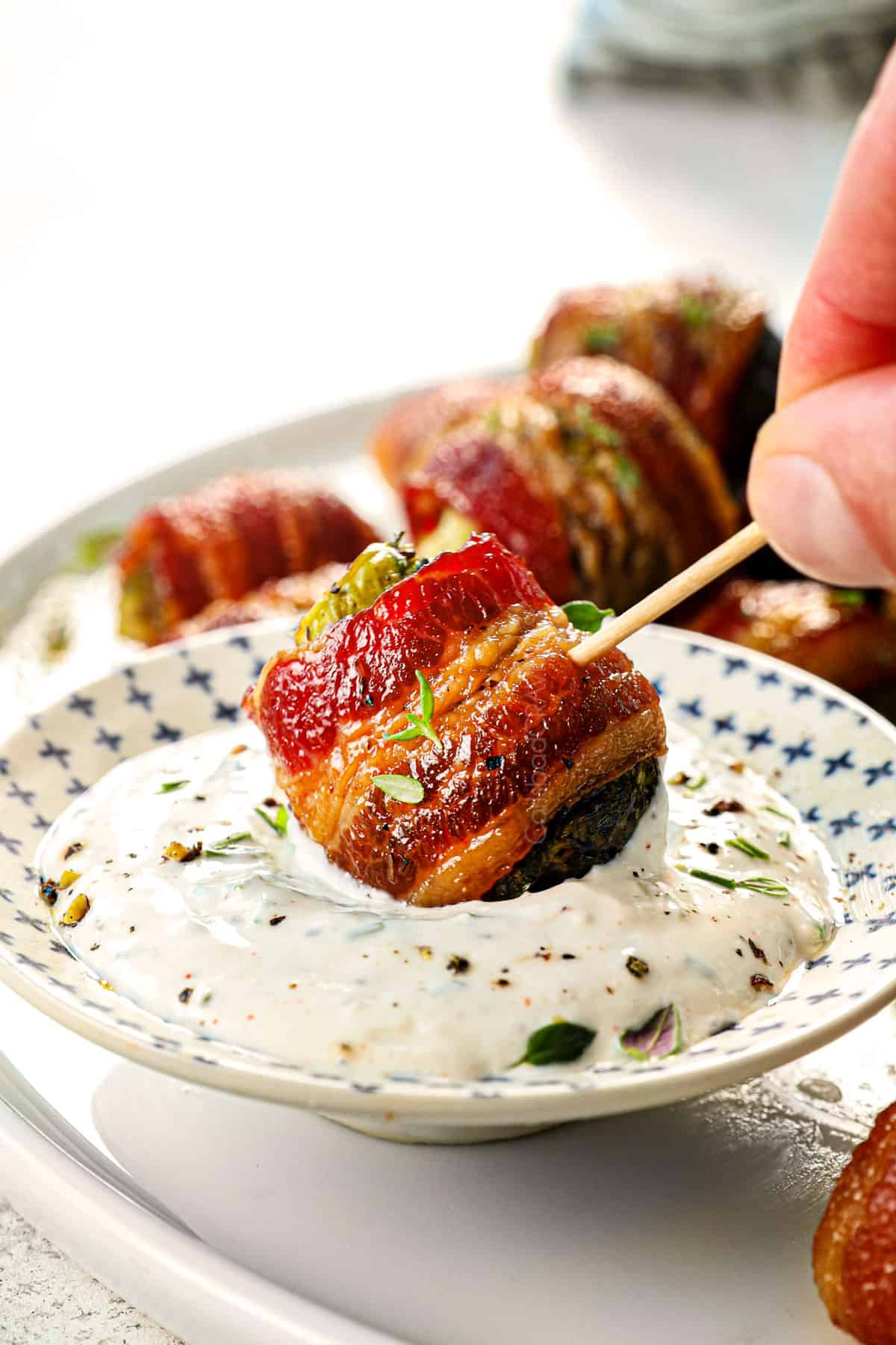 showing how to serve Bacon Wrapped Brussels Sprouts by dipping sprouts in Horseradish Sauce
