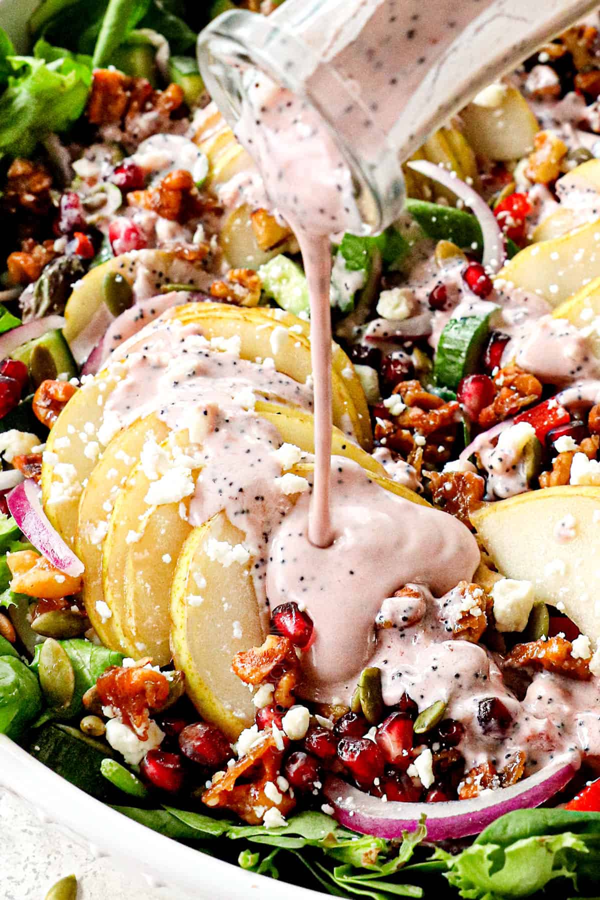 up close showing how to make pear salad recipe by drizzling with pomegranate dressing