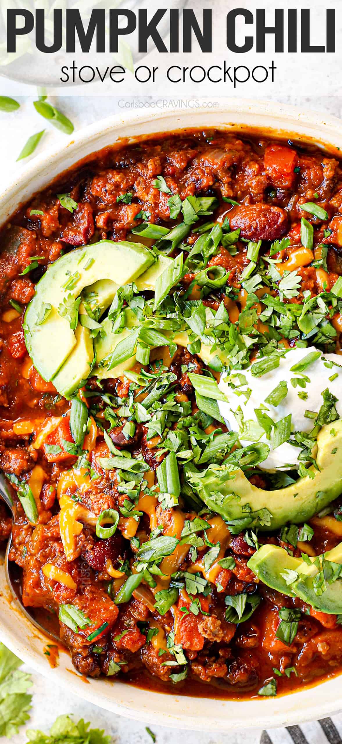 up close showing how to serve pumpkin chili by topping with cilantro, sour cream, avocados and cilantro