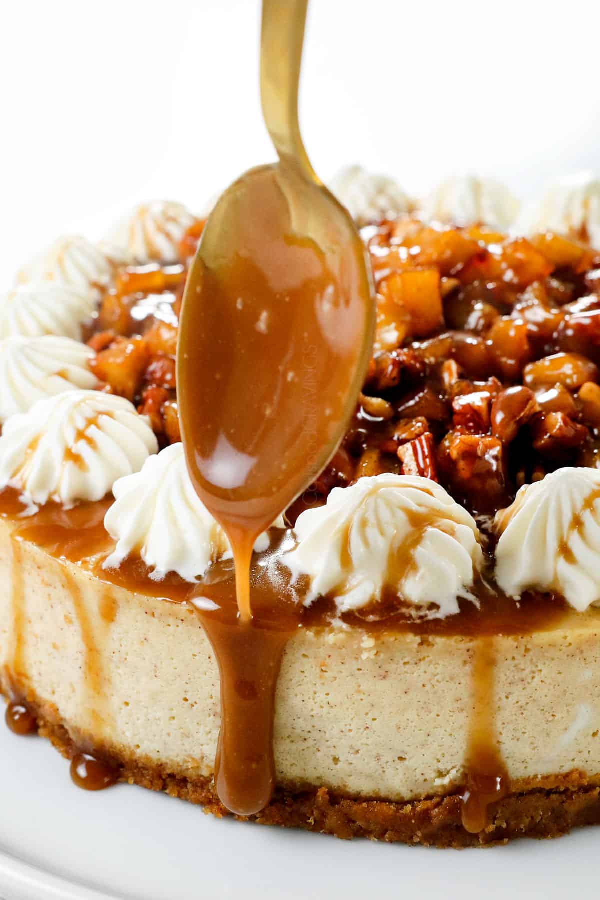 showing how to make caramel apple cheesecake by drizzling caramel over top 