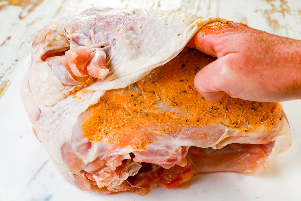 showing how to make roast turkey breast by rubbing herb butter under and over the skin of of the breast