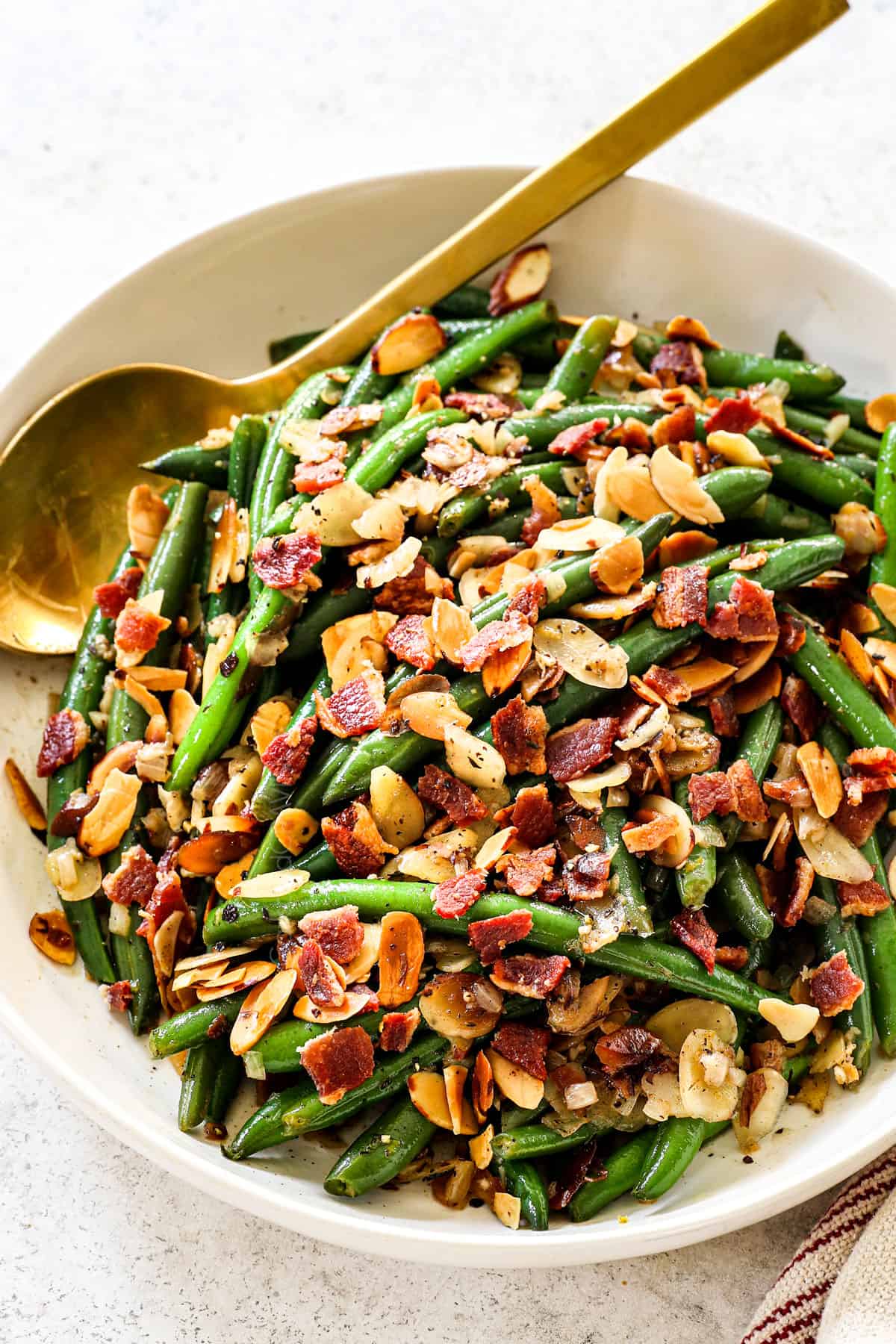 serving Green Beans Almondine in a bowl garnished by almonds and bacon