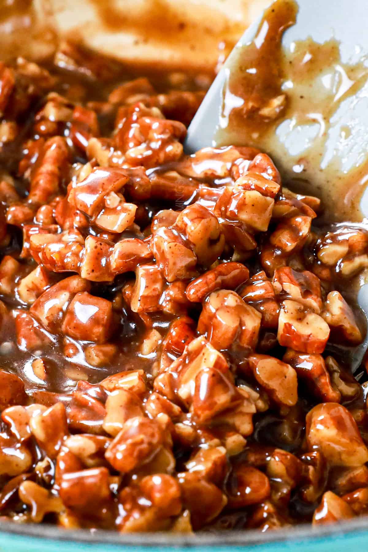 showing how to make pecan cookies with thumbprints by mixing the pecans with the caramel-like sauce
