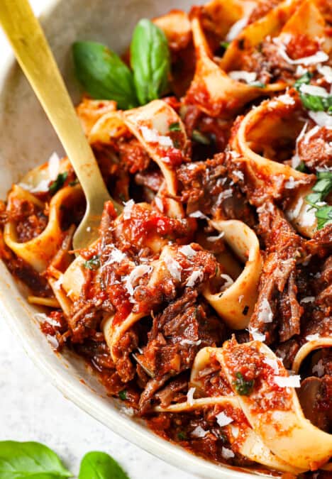 up close of twirling beef ragu recipe on a fork showing the saucy ragu sauce