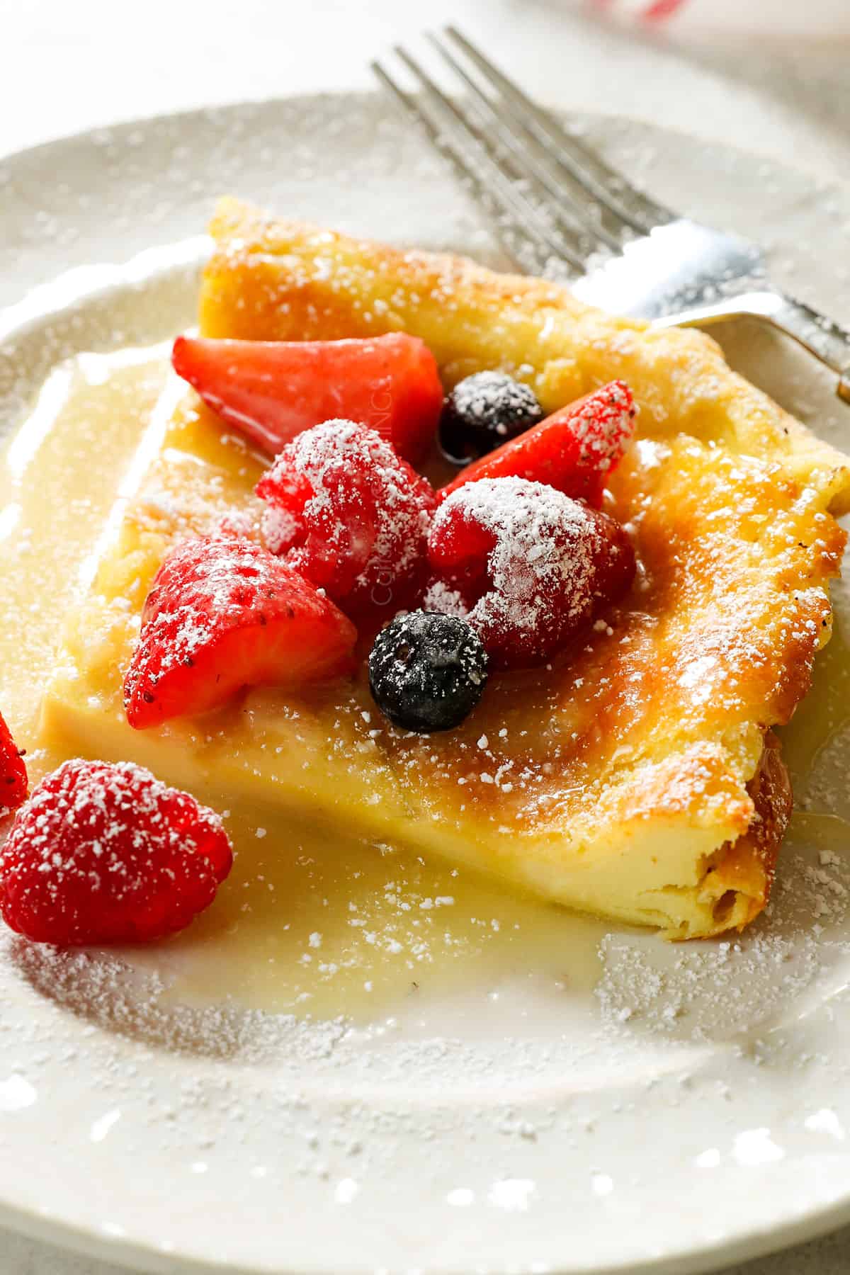 side view of German Pancake sliced and served on a plate with berries