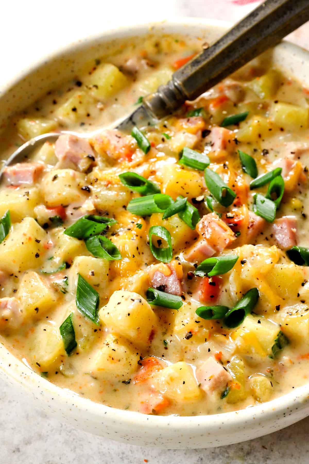 a bowl of potato and ham soup that's super creamy and cheesy