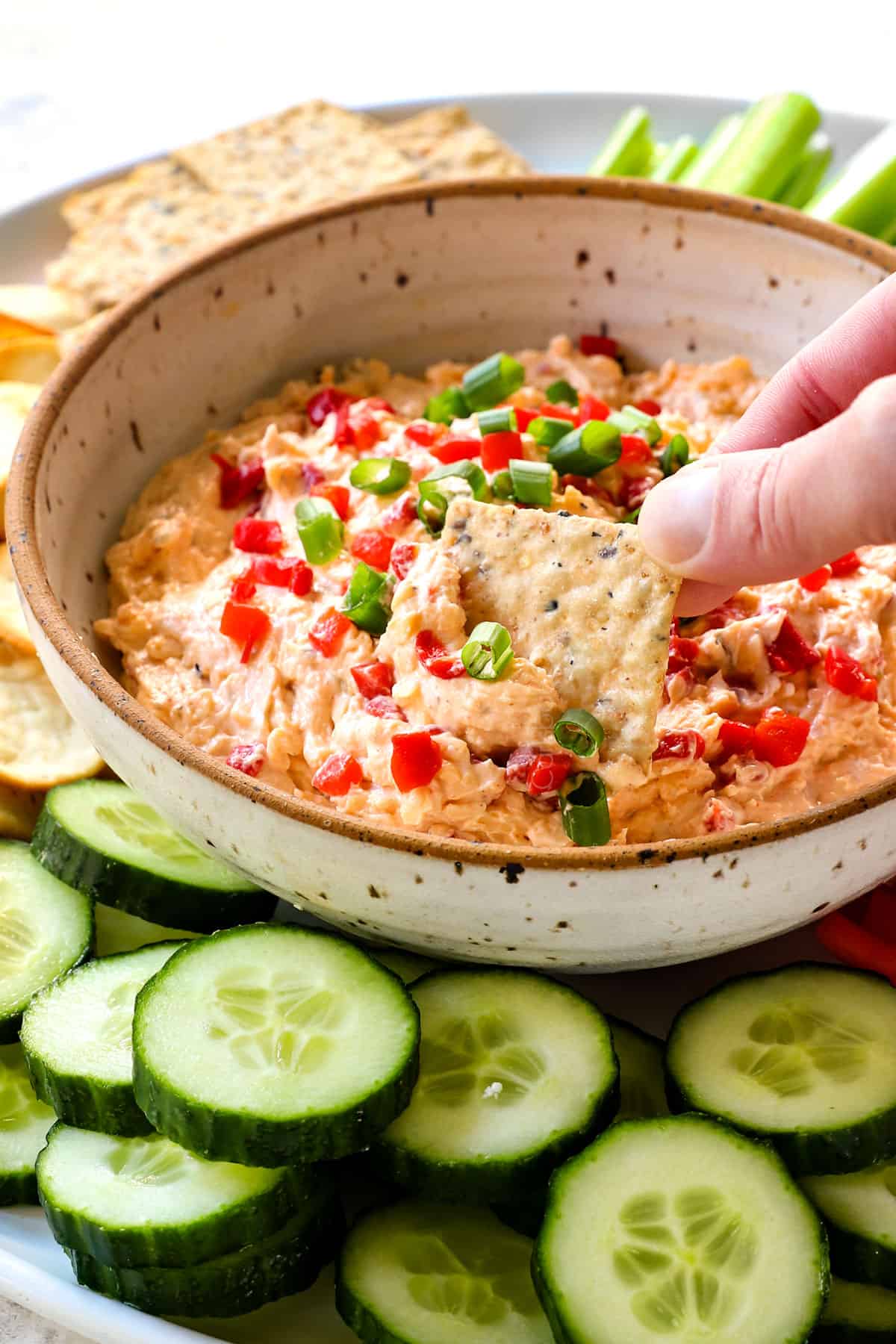 showing how to serve pimento cheese by dipping a cracker into the cheese