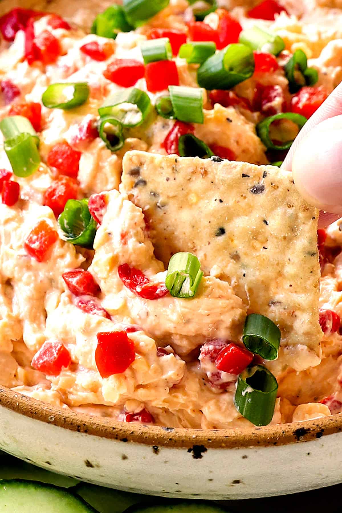 up close of dipping a cracker into pimento cheese recipe showing how rich and creamy it is
