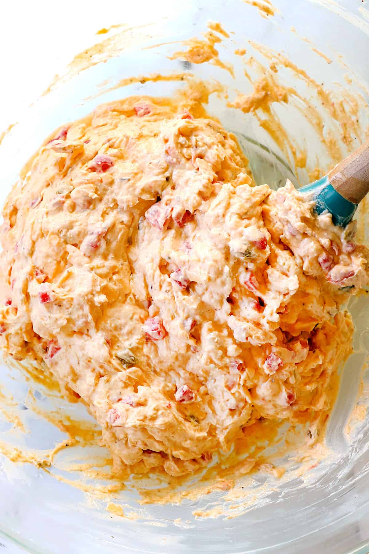 showing how to make pimento cheese recipe by mixing mayonnaise, cream cheese, cheddar and pimentos together in a glass bowl