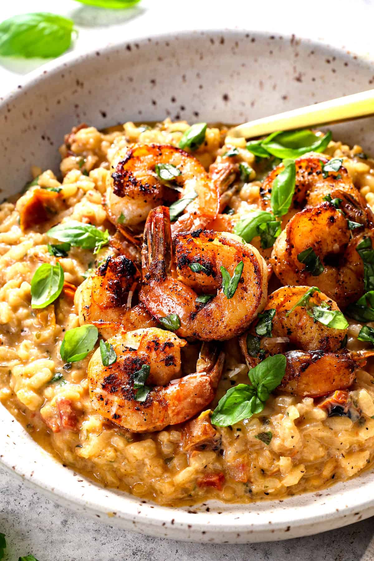 showing how to serve shrimp risotto by adding risotto to a bowl with shrimp on top