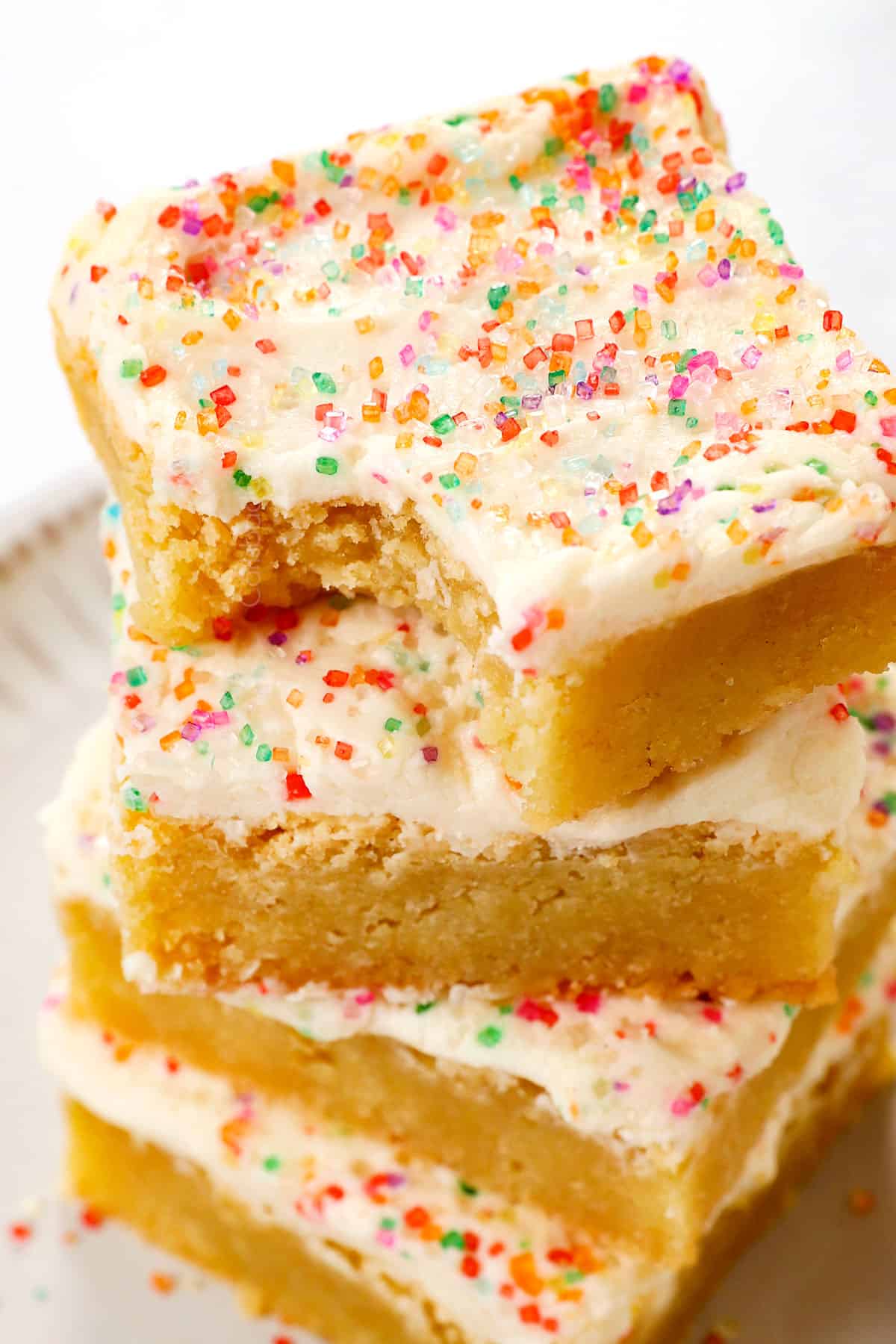 a stack of sugar cookie bars with cream cheese frosting with a bite taken out