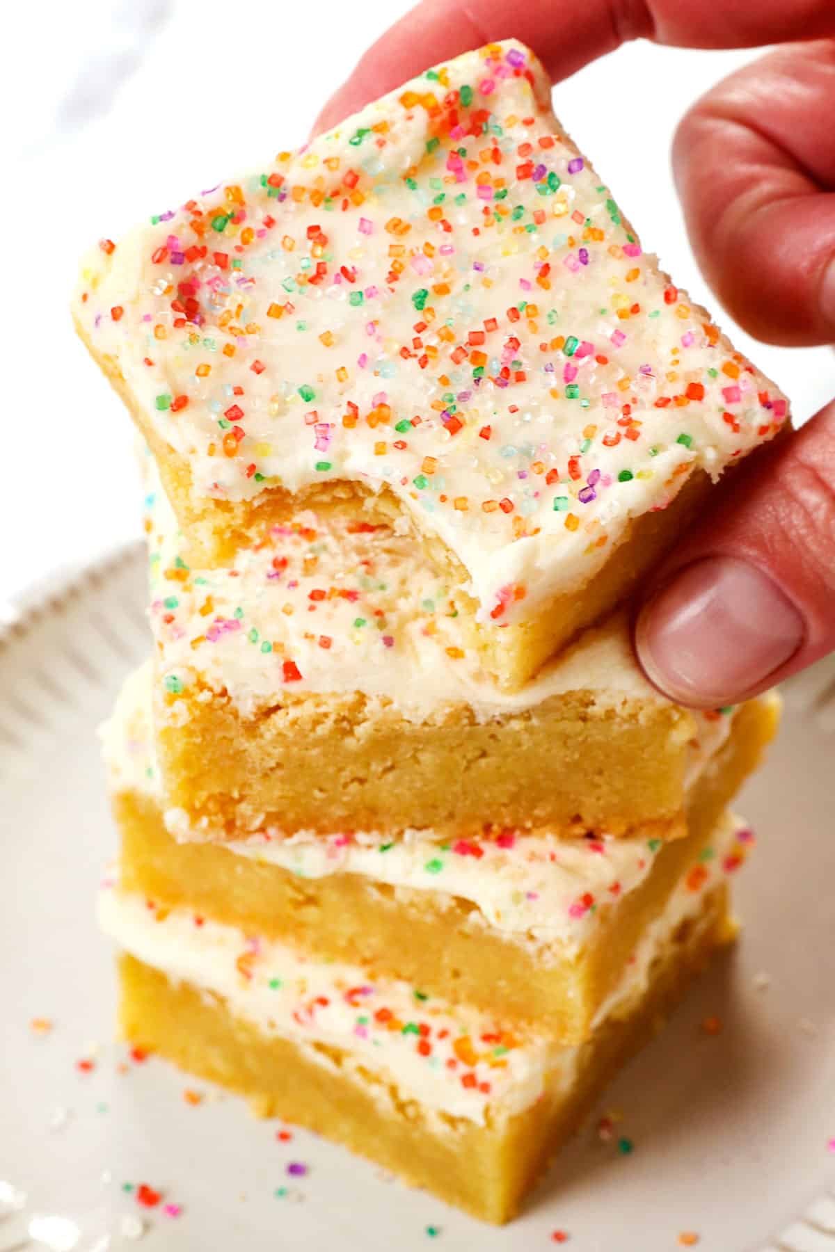 holding up a sugar cookie bar showing the frosting and sprinkles