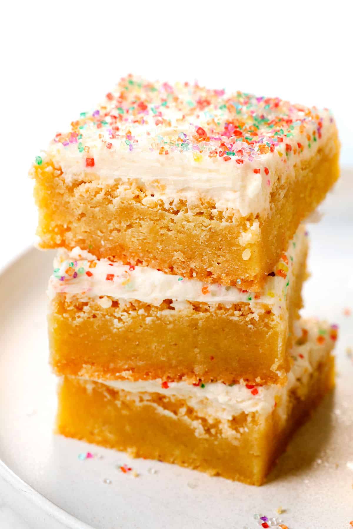 a stack of sugar cookie bars with cream cheese frosting decorated with sprinkles