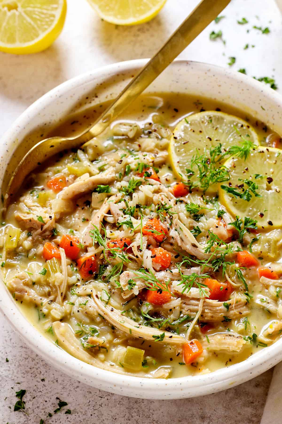 serving Avgolemono Soup (Greek Lemon Chicken Soup) in a bowl with chicken and rice 