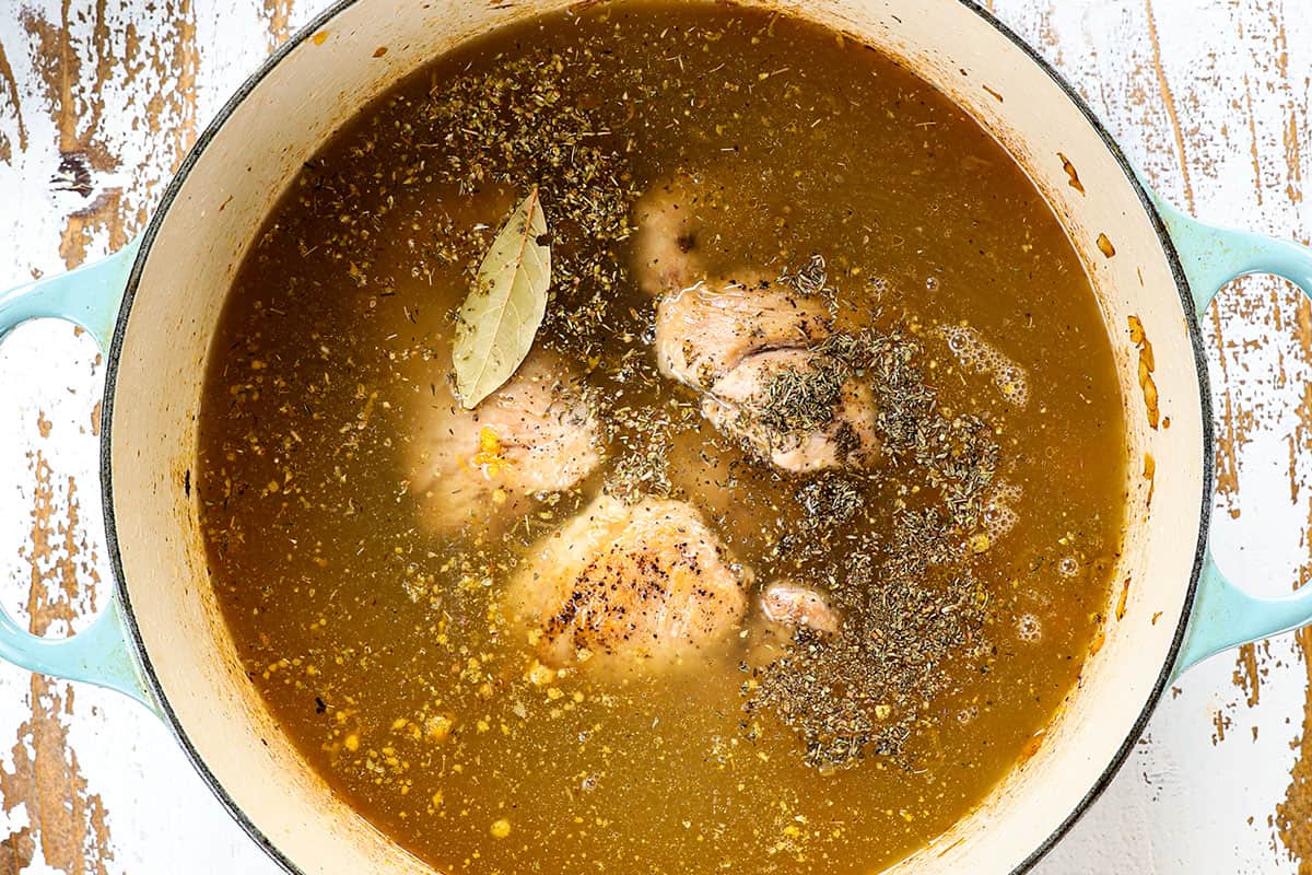 showing how to make traditional Avgolemono Soup recipe (Greek Lemon Chicken Soup) by adding the chicken, broth and spices to the soup pot to simmer
