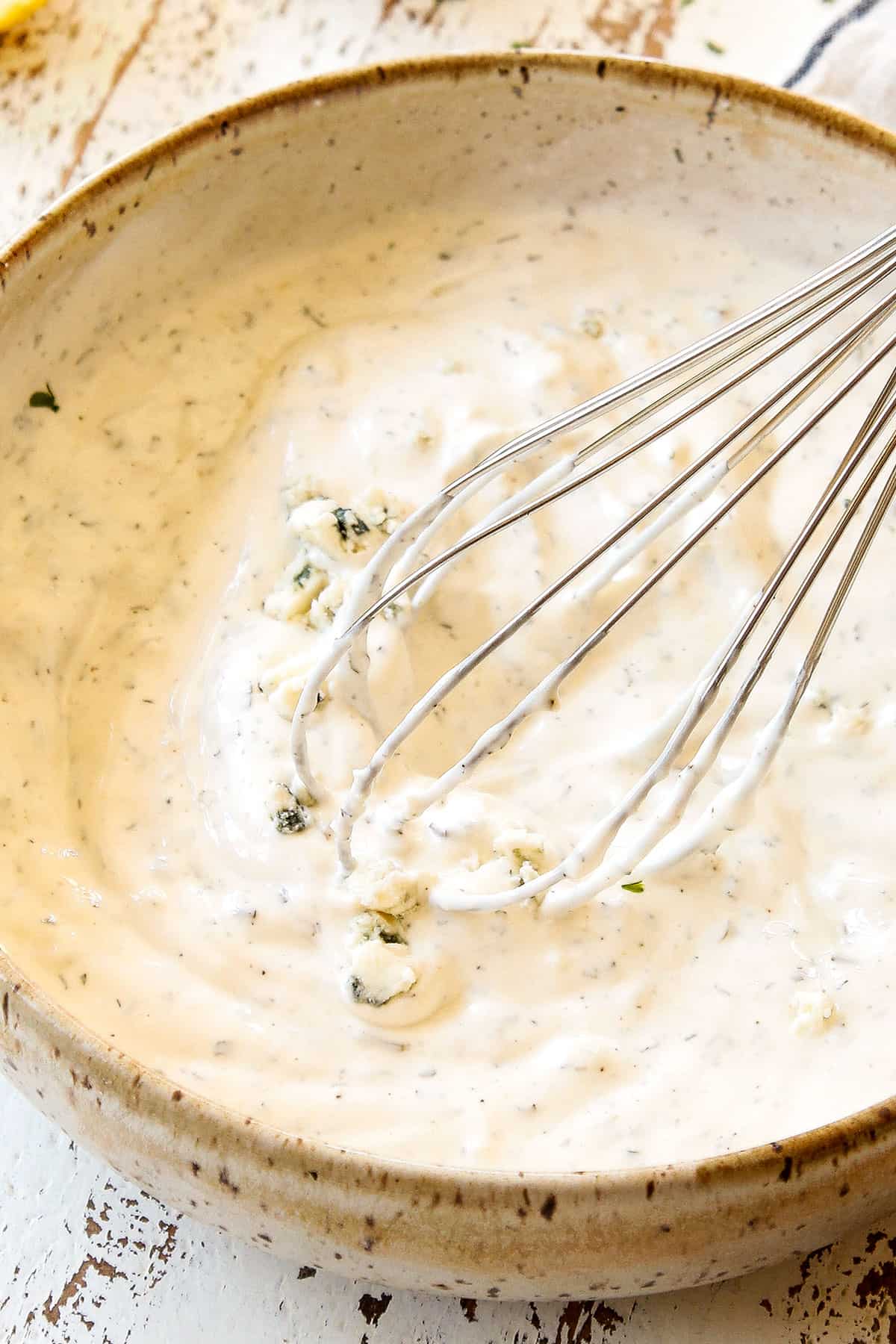 showing how to make blue cheese dressing by whisking the ingredients until smooth in a bowl