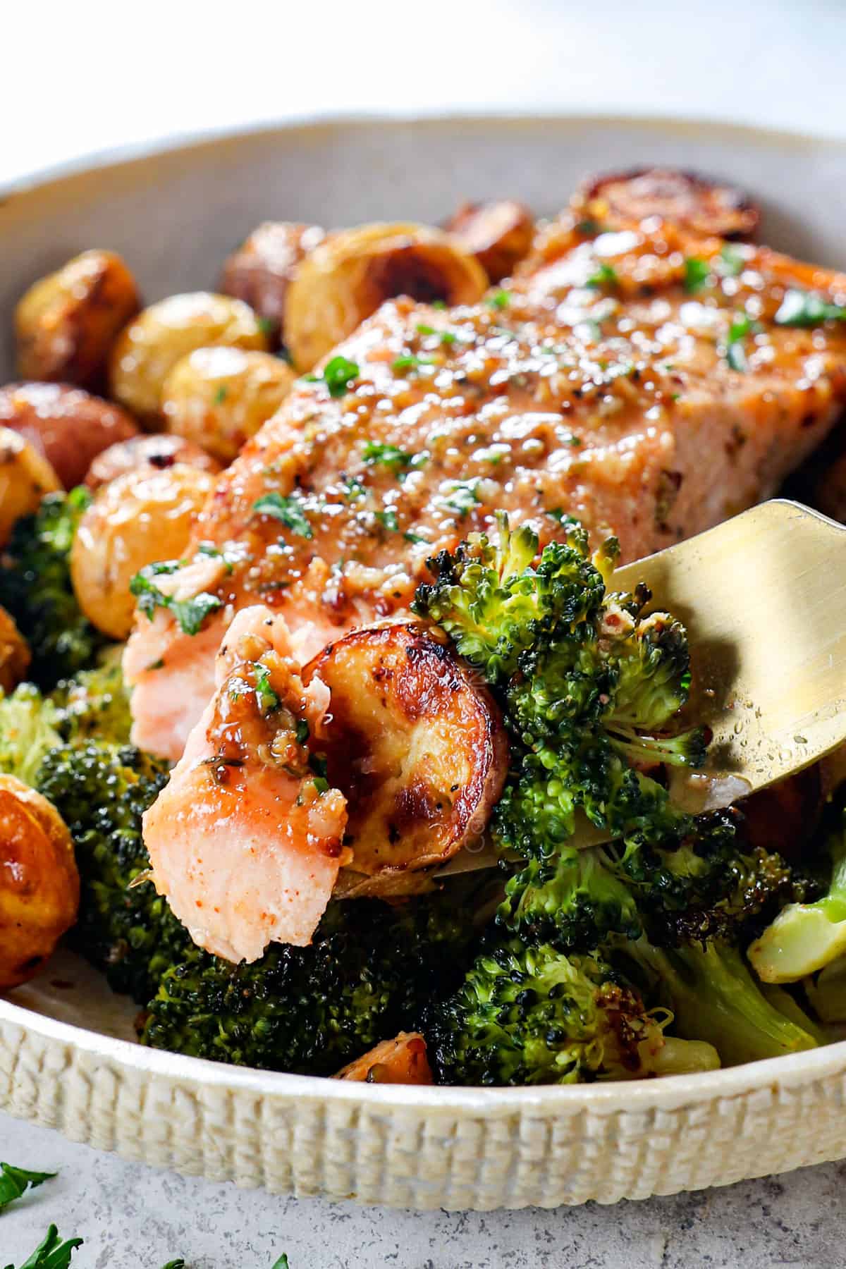 up close of taking a bite of honey mustard salmon with potatoes and broccoli on a fork