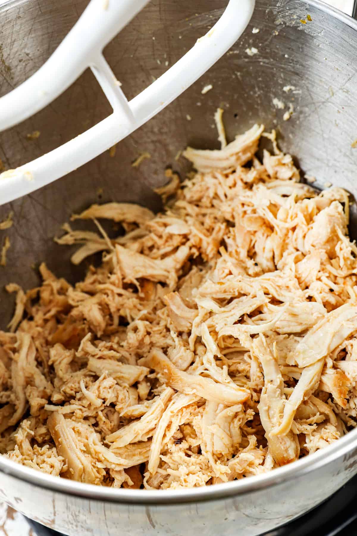 showing how to make shredded chicken by shredding it with the paddle attachment with a stand mixer