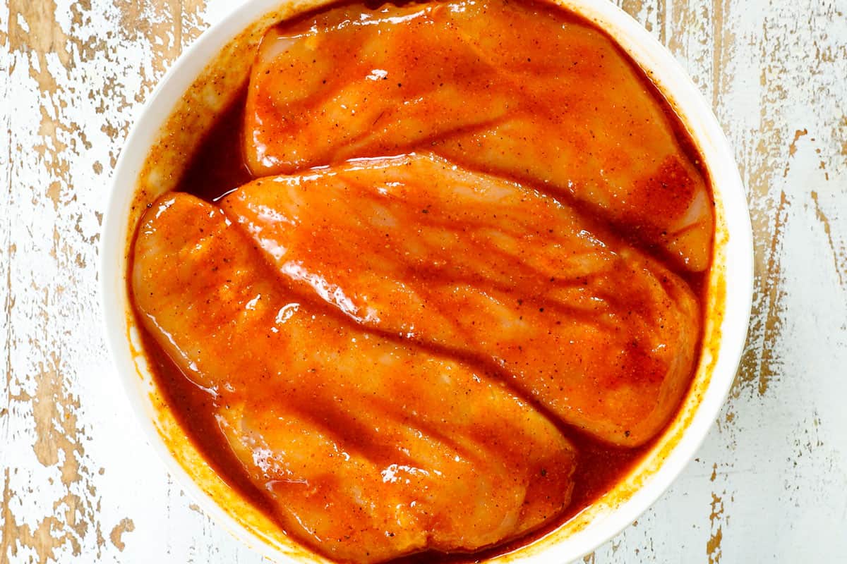 showing how to make buffalo chicken wraps by marinating chicken thighs in buffalo hot sauce