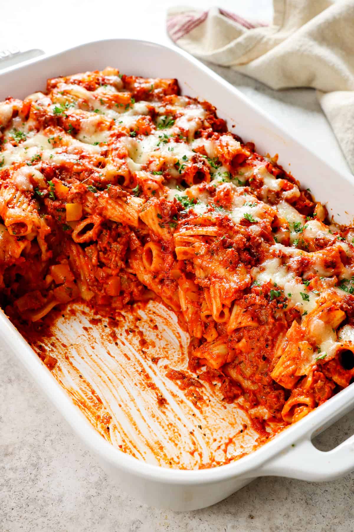 easy baked rigatoni recipe (rigatoni al forno) with portions removed from the casserole dish, showing the stack of rigatoni, sausage, and cheese