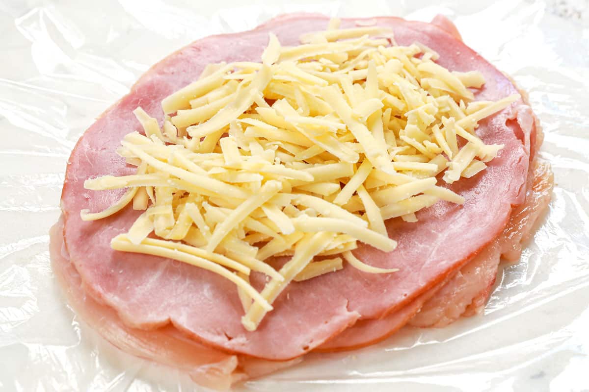 showing how to make chicken cordon bleu recipe by layering chicken breasts with ham and Swiss cheese