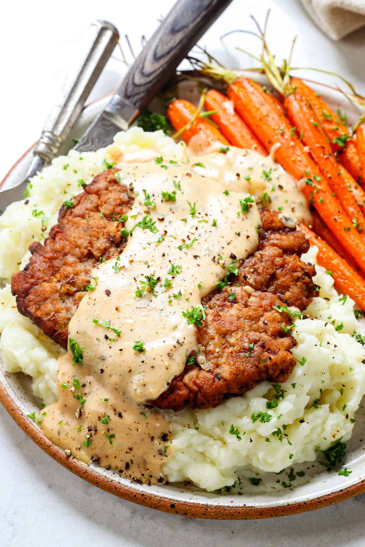 serving chicken fried steak with gravy and mashed potatoes