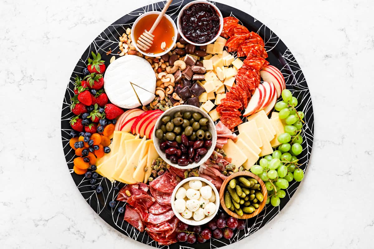 showing how to make a charcuterie board by adding nuts to the board