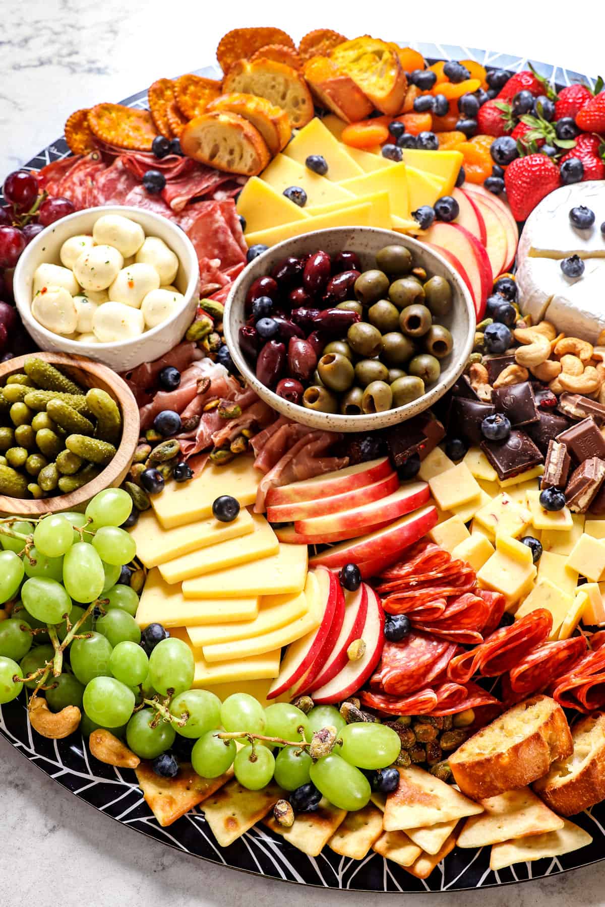 up close of a simple charcuterie board with cheeses, apples, grapes, meats and cheeses