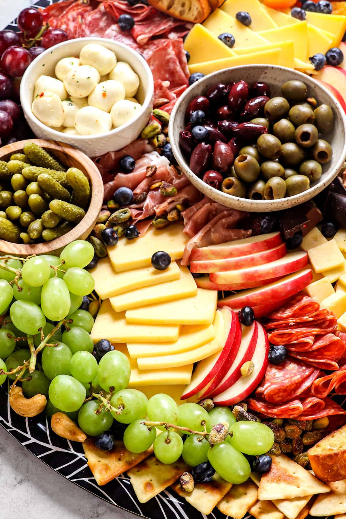 up close of a simple charcuterie board with cheeses, apples, grapes, meats and cheeses