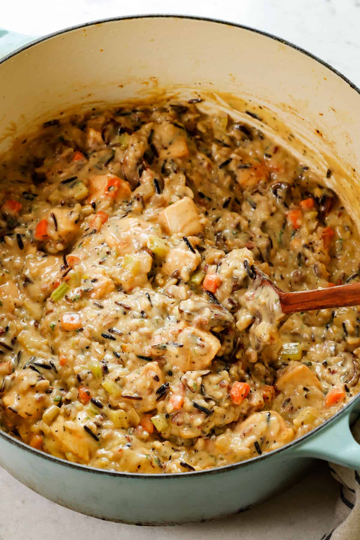 showing how to make chicken and wild rice casserole by adding chicken and rice the creamy sauce and stirring to combine