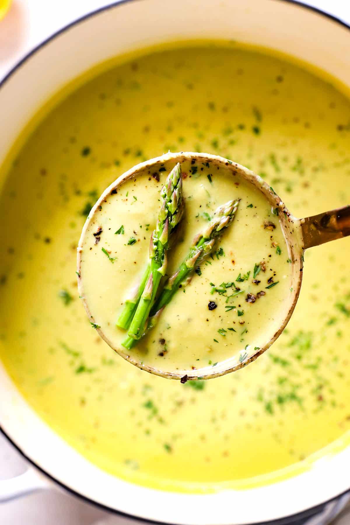 scooping up a ladle of Cream of Asparagus Soup recipe showing how creamy it is