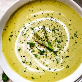 top view of Creamy Asparagus Soup in bowls garnished by asparagus spears and fresh dill