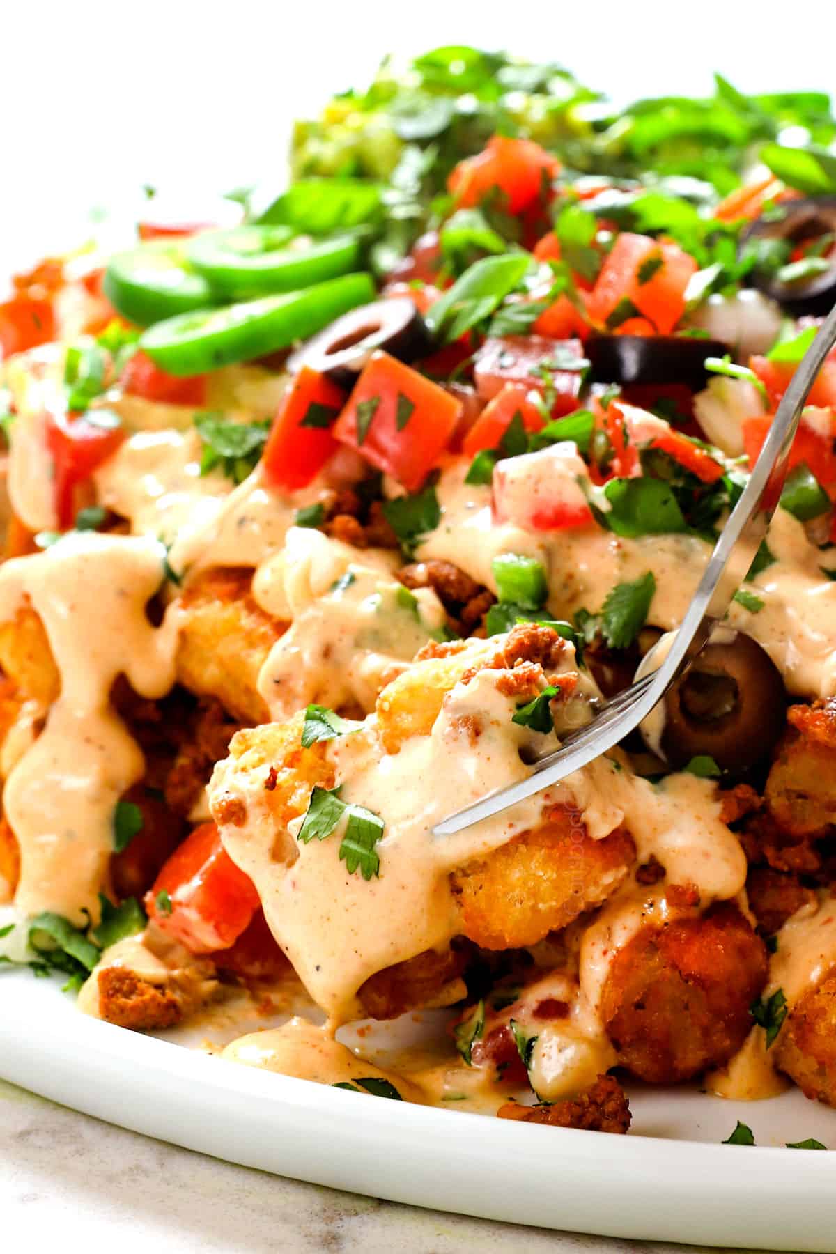 showing how to eat tater tot nachos (totchos) by eating the tater tots with a fork