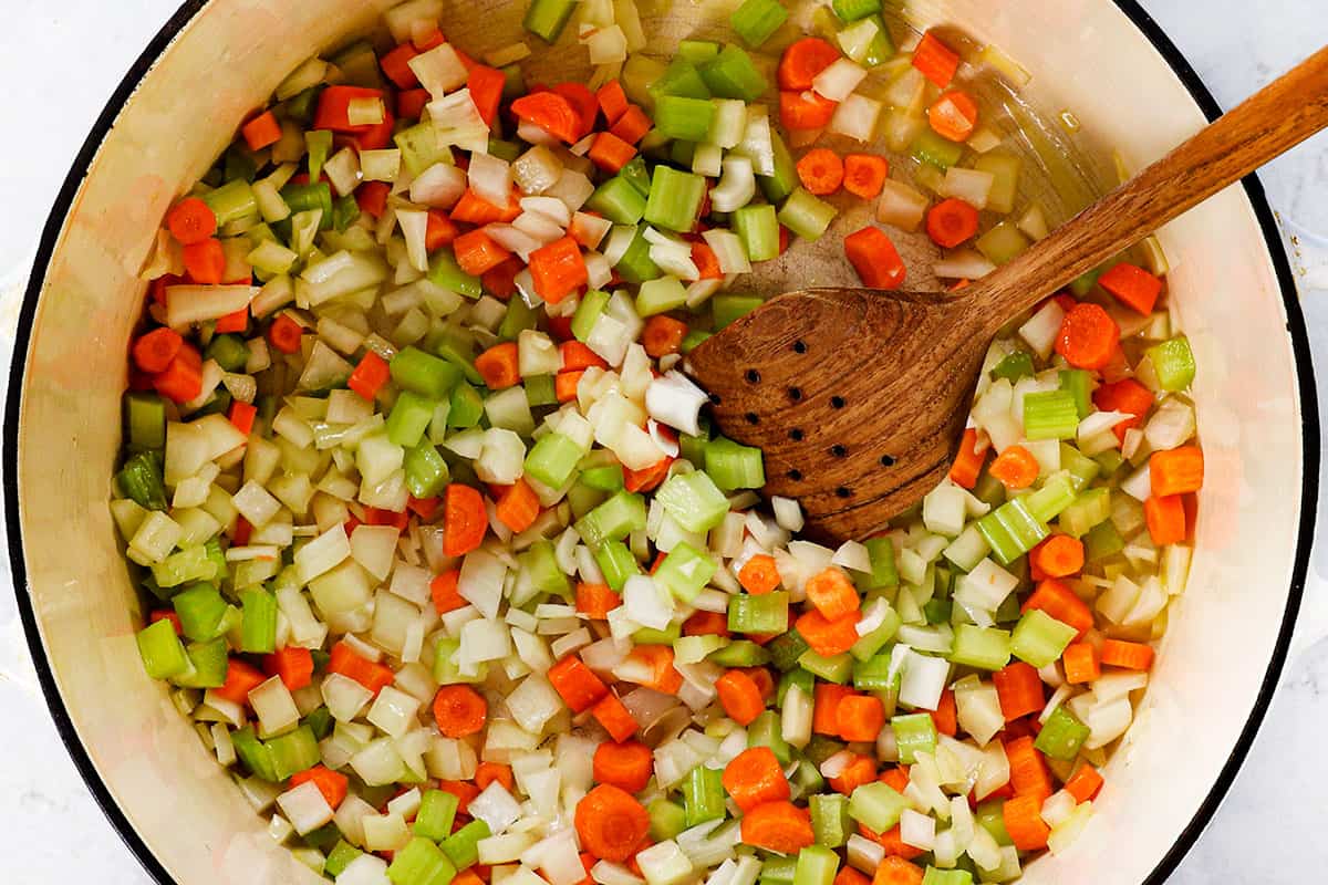 showing how to make ham and bean soup by sautéing onions, celery and carrots in a Dutch oven