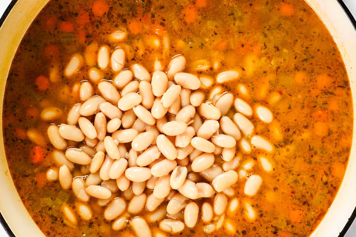 showing ho to make ham and bean soup by adding white beans to the broth to simmer