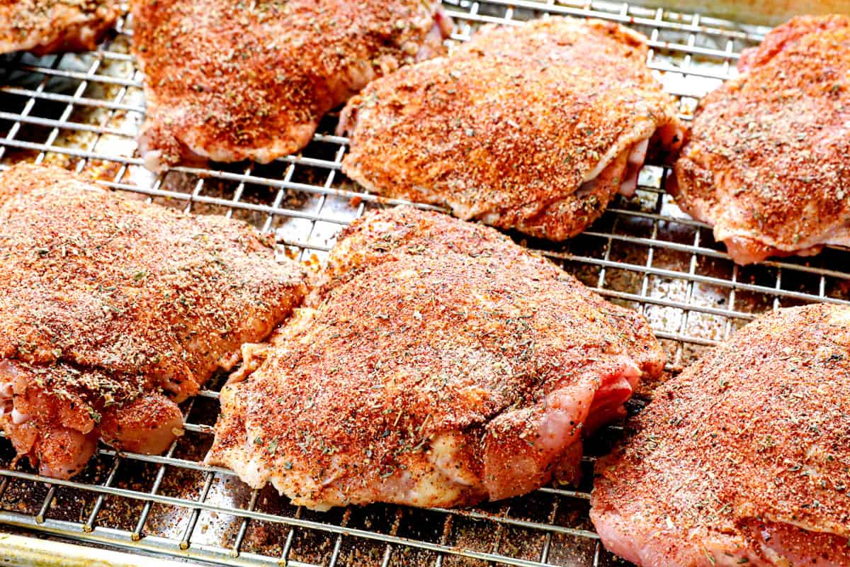 showing how to bake chicken thighs by adding the spice rub to both sides of the chicken