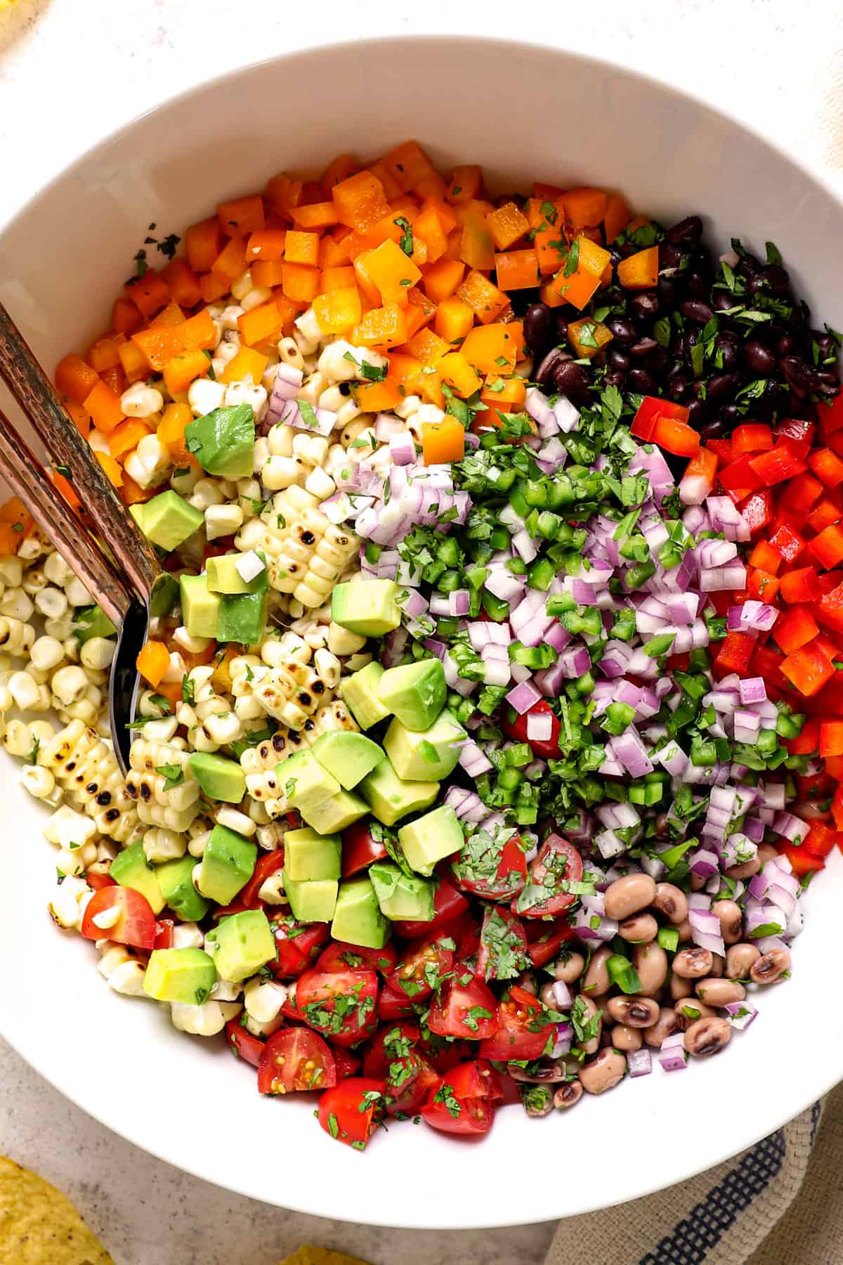 top view ingredients in recipe for cowboy caviar (Texas Caviar recipe) including black eyed peas, black beans, tomatoes, bell peppers, corn and cilantro