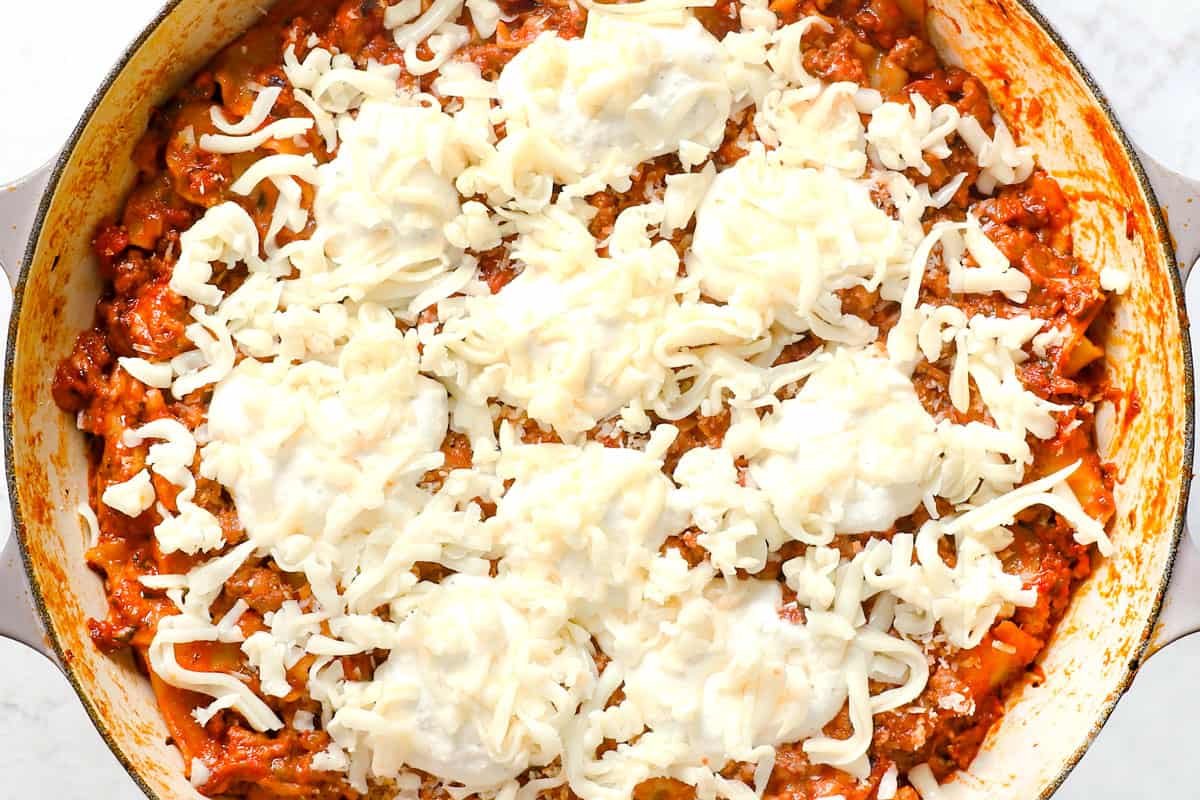 showing how to make easy lasagna recipe in a skillet by dolloping with ricotta and topping with mozzarella and Parmesan before baking